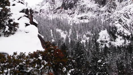 Aerial-Drone-footage,-flyover-cliff-and-drop-off-over-Yosemite-valley,-blanketed-in-snow-in-winter