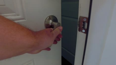close-up-of-hand-turning-door-knob-to-open-door-into-apartment-to-reveal-the-other-side