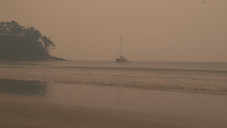Lone-Boat-In-Ocean-Water-Surrounded-By-Smoke-From-Nearby-Bushfire,-Bruny-Island,-Tasmania,-Australia