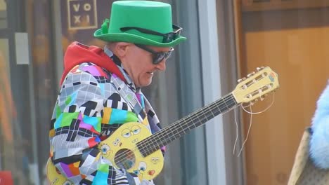 Colourful-Liverpool-city-busker-performing-in-patterned-suit,-sunglasses---green-hat-with-guitar