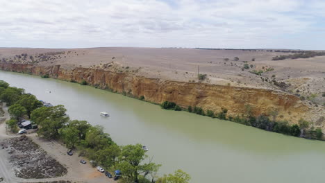 Aerial-shot-moving-across-the-stunning-River-Murray-and-limestone-cliffs-as-boats-cruise-down-the-river-in-South-Australia