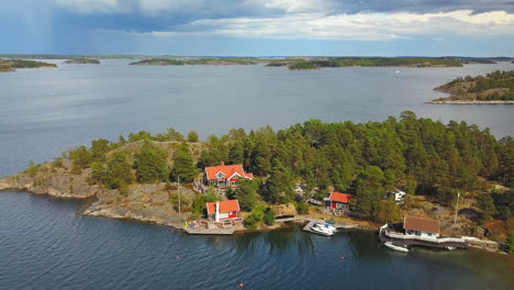 Aerial,-orbit,-drone-shot,-panning-towards-summer-houses,-on-a-island,-in-the-Swedish-archipelago,-at-the-baltic-sea,-Dark-sky,-on-a-sunny,-summer-evening,-in-Sweden