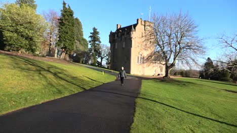 Crathes-Castle-in-winter-sun-with-lady-walking-past
