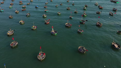 Aerial-shot-over-hundreds-of-traditional-conical-basket-boats-and-trawler-fishing-boats-in-Vietnam,-Asia