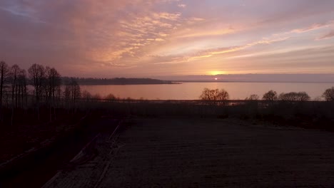 Lake-Burtnieks-Im-Spätherbst-Roter-Himmel-Sonnenuntergang-Luftbild-Weitblick-Mit-Baumsilhouette