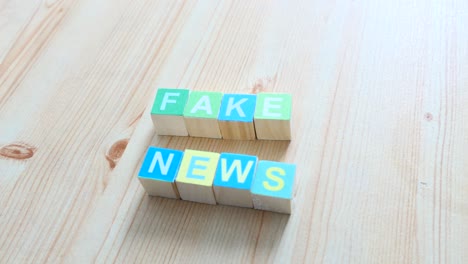 Hand-bringing-Fake-News-written-on-Wooden-Cubes