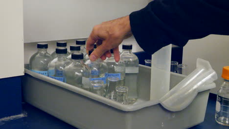 Nahaufnahme-Eines-Wissenschaftlers,-Der-Einen-Behälter-Mit-Destilliertem-Wasser-Für-Ein-Experiment-In-Einem-Medizinischen-Forschungslabor-Ersetzt