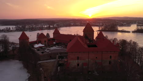 AERIAL:-Flying-in-to-the-Sunset-Over-Trakai-Castle-Above-Frozen-Lake