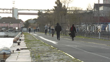 People-walking-the-river-Tagus-at-sunset-near-the-25-Th-April-Bridge
