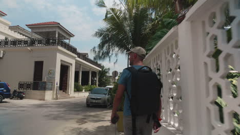 Tourist-walking-on-the-street-of-Zanzibar-Stone-Town-with-palm-trees-and-restaurants-around