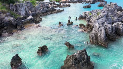 Aerial-view-of-sharp-pointy-rocks-in-turquoise-water-by-tropical-island