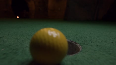Ein-Gelber-Minigolfball-Fällt-In-Das-Golfloch-Und-Springt-In-Der-Tasche-Auf-Einem-Kurs