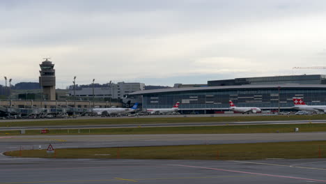 An-airline-aircraft-taxiing-to-the-gate-in-front-of-the-terminal-at-a-busy-airport