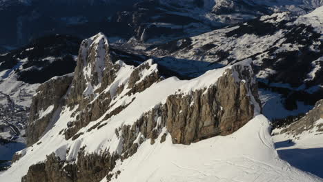 Aerial-view-of-a-sideways-pan-left-of-a-snow-covered-mountain-ridge-in-the-French-Alps-with-evening-light-near-La-Clusaz
