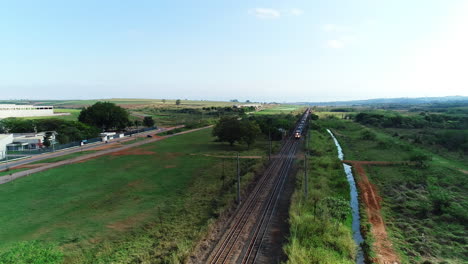 aerial-video-of-train-crossing-the-field-close-to-the-city,-Brazil