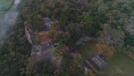 AERIAL:-Aerial-shot-of-Mayan-archaeological-site-amid-deep-green-forest-in-Copan,-Honduras