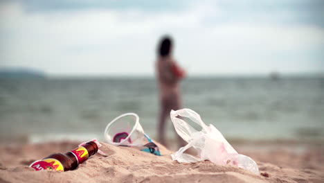 Plastic-pollution-and-a-woman-on-the-background-on-a-beach-in-Sihanoukville,-Cambodia