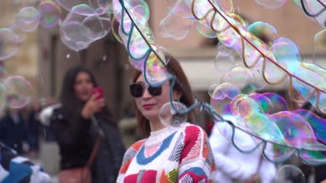 Middle-aged-Chinese-woman-in-bright-sweater-playing-with-soap-bubbles-at-Prague-main-square