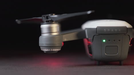 Track-across-the-rear-and-propellers-of-a-white-DJI-Spark-drone-with-drone-lights-flashing