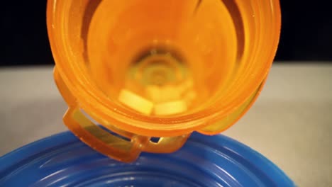 speeding-past-empty-bottle-cap,-very-slowly-pushing-into-the-length-of-a-prescription-pill-bottle,-shallow-focus-to-reveal-details