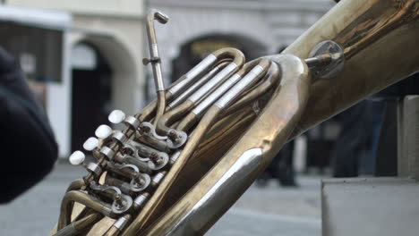 A-giant-brass-instrument-lies-against-stair-on-the-street-as-a-child-steps-past-in-Melnik,-Czech-Republic