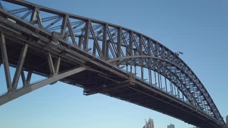 Wunderschönes-Schwenken-Und-Nahaufnahme-Der-Sydney-Harbour-Bridge-Unterhalb-Der-Brücke-Bei-Sonnenuntergang