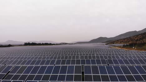 Aerial-Shot-going-forward-barely-above-ground-over-Solar-panels-in-Photovoltaic-Plant,-Chile-4K