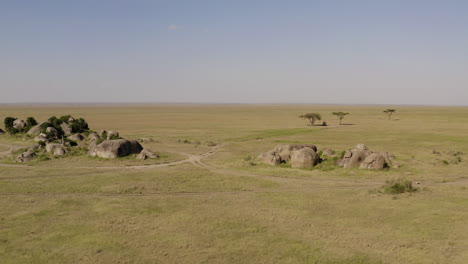 Stone-Islands-Und-Ein-Safari-Tour-Auto,-Das-Im-Schatten-Des-Baumes-Im-Serengeti-Nationalpark,-Tansania,-Geparkt-Ist