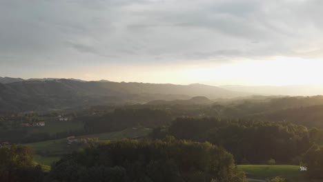a-professional-looking-aerial-shot-of-the-austrian-alps,-while-sunset,-over-some-vineyards-in-a-slight-circular-movement-with-lenseflare