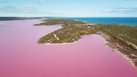 Aerial-wide-shot,-large-pink-water-lagoon,-blue-ocean-in-background