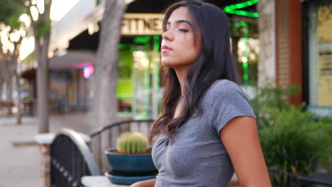 A-beautiful-hispanic-woman-standing-and-posing-on-the-urban-city-street-full-of-shops-and-retail-stores-SLOW-MOTION