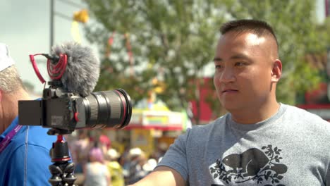 Asian-vlogger-starting-to-record-himself-with-a-camera-at-a-carnival-fair-in-4K-slow-motion