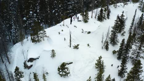 Aerial-backward-pan-up-shot-from-a-group-of-people-on-a-snowy-mountain