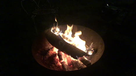 Logs-burning-in-a-fire-bowl-on-a-pitch-black-night