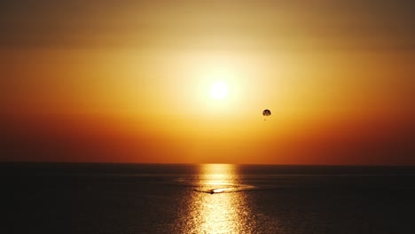 Parasailing-Parascending-Parakiting,-Paragliding-Bei-Filmischem-Sonnenuntergang-Mit-Dem-Boot-In-Zehn-Bit-Vier-K-Sechzig-Fps-In-Entfernung