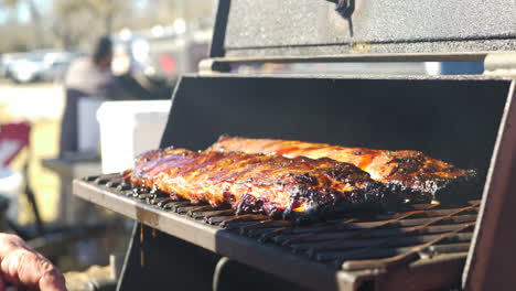 A-man-pouring-BBQ-Sauce-on-to-a-rack-of-ribs-and-placing-them-in-a-smoker