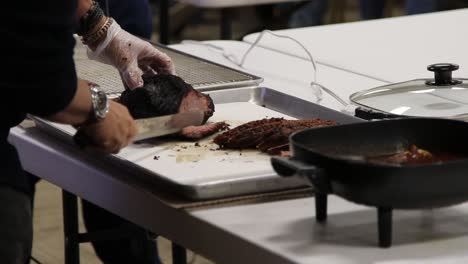 Instructor,-author,-and-chef-cutting-first-piece-of-brisket-off-the-point-end,-and-illustrating-using-non-cutting-hand-to-held-the-brisket-from-sliding-as-you-cut-it