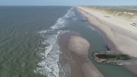 Olas-De-Playa-En-Las-Dunas-Holandesas-Y-Gente-Caminando-En-La-Playa-Vista-De-Drones