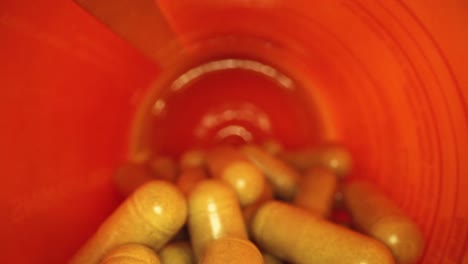 slowly-pulling-out-of-an-orange-supplement-pill-bottle,-revealing-bottle's-cap