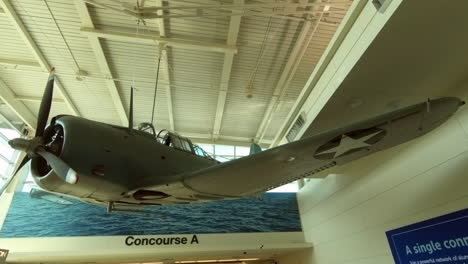Dauntless-Dive-Bomber-hangs-from-the-ceiling,-memorial-exhibit,-war-plane,-aircraft-model-decor-in-Chicago-airport,-connection-concourse,-Usa,-United-States,-aviation-history,-mural-airport-art