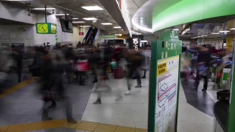 Time-lapse-of-gates-at-Shinjuku-Station,-with-people-stoping-at-an-information-board-to-find-which-exit-is-best