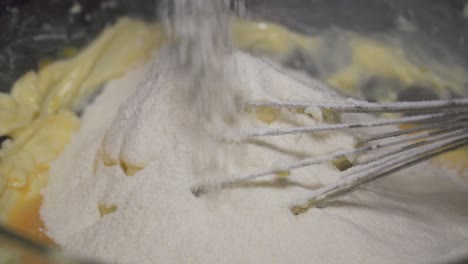 Slow-motion,-home-baker-pouring-flour-in-a-bowl-with-ingredients