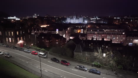 Panning-shot-of-Edinburgh-at-night-from-Edinburgh-castle-with-people-walking-and-cars-passing-below