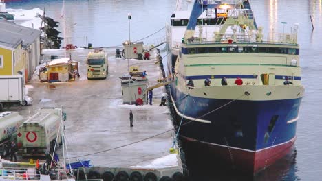 Großes-Transportschiff,-Das-Waren-Transportiert,-Die-Von-Seeleuten-Auf-Dem-Dock-Einer-Nördlichen-Küstenstadt-In-Norwegen-Entladen-Werden-Tromso