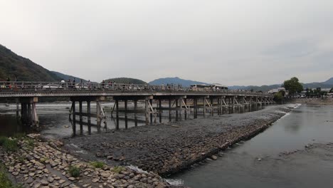 Los-Turistas-Cruzan-El-Puente-Togetsukyo-Sobre-El-Pacífico-Río-Katsura,-Kyoto