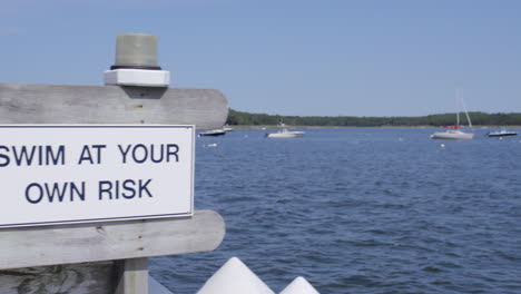 Swim-At-Your-Own-Risk-sign-on-a-dock-at-the-lake-in-Cape-Cod