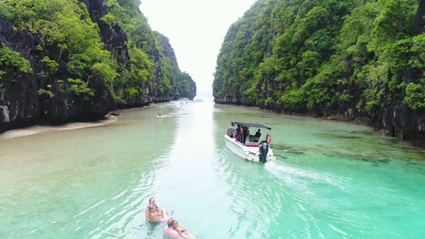 Following-A-Speed-Boat-Driving-Through-Clear-Water-Passage-Between-Two-Mountains-In-Palawan-Philippines