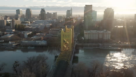 Aerial-drone-tilt-up-and-push-past-Tower-Bridge-and-Downtown-Sacramento,-CA,-including-Old-Sacramento---State-Capitol-in-background-during-sunrise