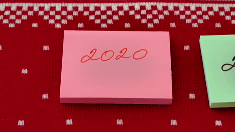 Hand-moving-Post-It-note-stack-with-another-with-change-of-year-against-red-design-background