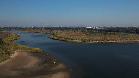 aerial-right-pan,-orbit-over-Shell-Bank-Creek-in-Brooklyn,-with-the-creek-shore,-horizon---water-in-view-with-blue-skies-and-no-clouds